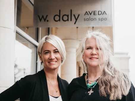 Two women smiling outside W. Daly Aveda Salon Spa.