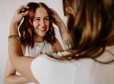 Woman smiling while another styles her hair for a special occasion.