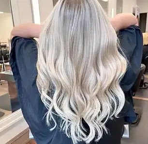 Blonde hair with loose waves viewed from the back in a modern salon setting.