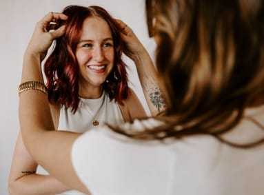 Woman smiling while another styles her hair for a special occasion.