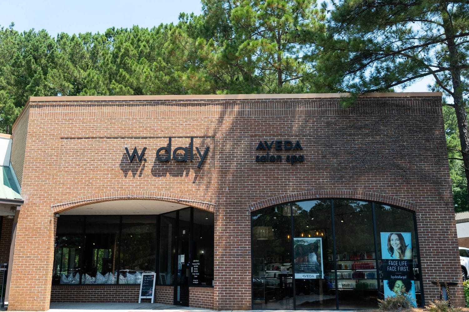 Exterior of W. Daly Aveda salon and spa with brick facade and large glass windows.